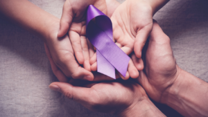 hands with a violet ribbon for cancer awareness
